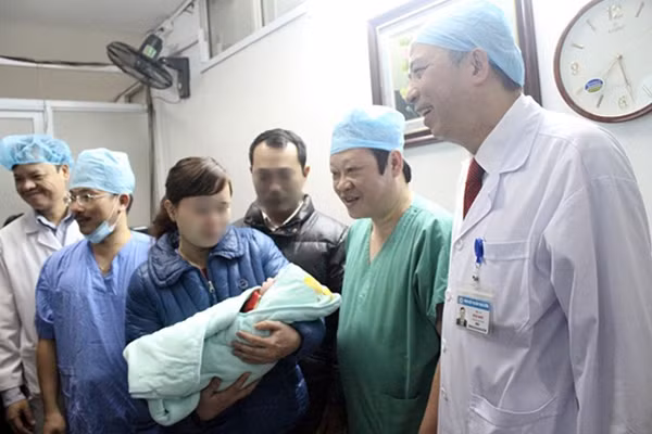 Thứ trưởng Bộ Y tế, GS.TS Nguyễn Viết Tiến (đứng thứ hai từ phải sang trái) vui mừng khi trao con cho cặp vợ chồng hiếm muộn.