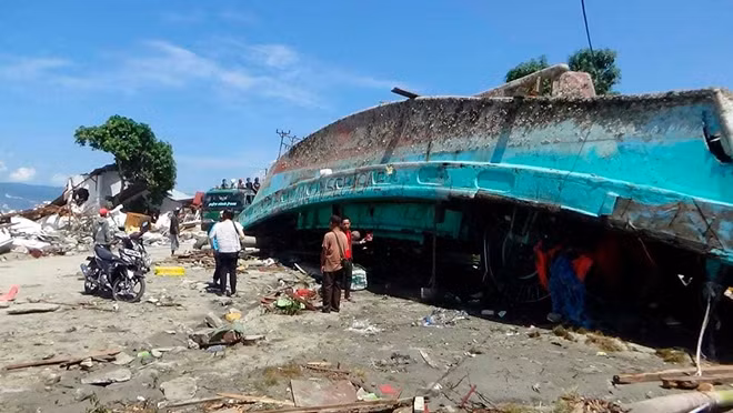 Một con thuyền bị lật úp và bị đánh xô vào bãi biển sau khi sóng thần đổ ập xuống. Ảnh: AP