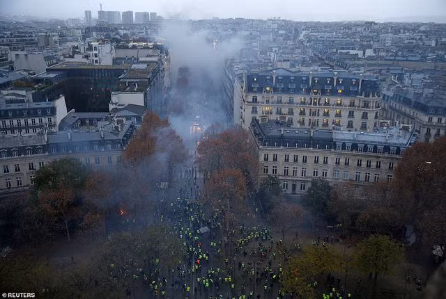 Paris bỗng chốc nhuốm màuvàng dữ dội bởi những người biểu tình lẫn với màu xám hoang tàn bởi hàng loạt pháo khói mà đám đông quá khích sử dụng. Ảnh: Reuters