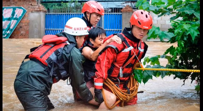 Một người dân sống trong tâm lũ được lực lượng cứu hộ đưa đi di dời. Ảnh: Reuters