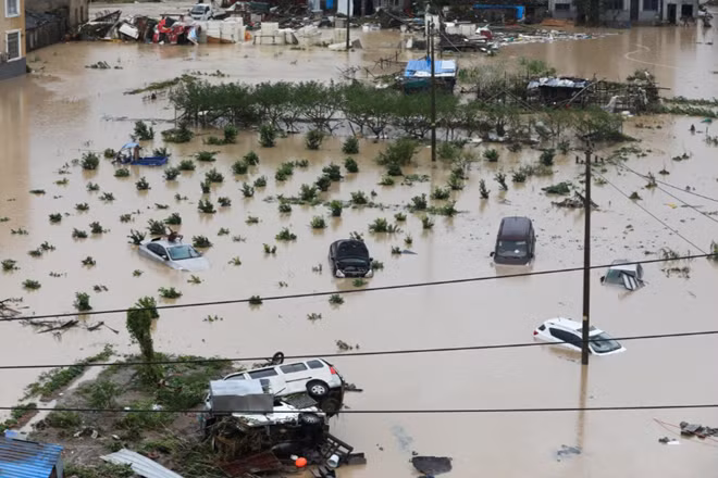 Các phương tiện giao thông bị cuốn trôi theo dòng nước lũ. Ảnh: Reuters