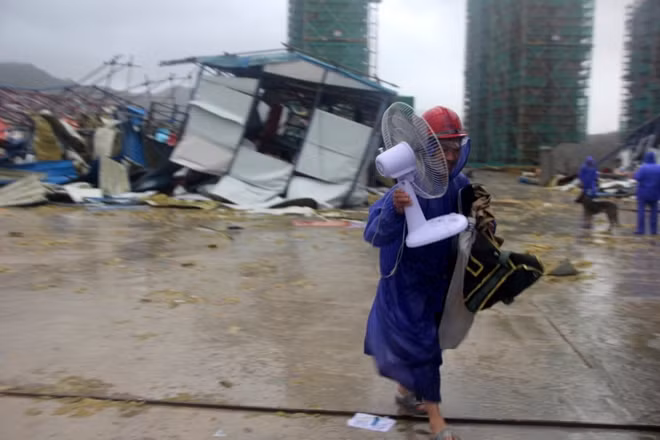 Một công nhân tại thành phố Ôn Lĩnh vội vã sơ tán những đồ đạc quan trọng sau khi khu ký túc xá của anh bị bão tàn phá. Ảnh: AP