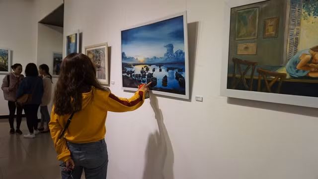 Một bạn trẻ đang chăm chú ngắm nhìn bức tranh được thực hiện bởi những họa sĩ không chuyên tại triển lãm. Một bạn trẻ đang chăm chú ngắm nhìn bức tranh được thực hiện bởi những họa sĩ không chuyên tại triển lãm.