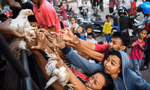 Những người dân giành giật hàng viện trợ. Ảnh: The Guardian Những người dân giành giật hàng viện trợ. Ảnh: The Guardian