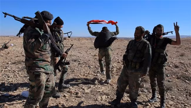Các lực lượng ủng hộ chính phủ Syria giơ dấu hiệu V sau khi chiếm đóng thành công một ngọn đồi gần thị trấn Mahin, tỉnh Homs. Ảnh: Press TV