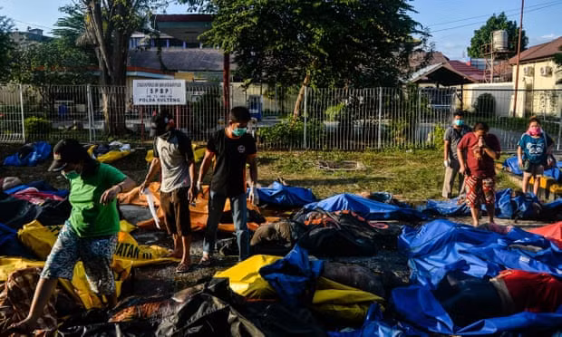 Lực lượng cứu hộ tìm kiếm các thi thể được bọc trong túi nilon. Ảnh: Reuters