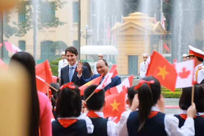 Thủ tướng Nguyễn Xuân Phúc và Thủ tướng Canada Justin Trudeau vẫy tay chào các em nhỏ trong đội chào mừng.