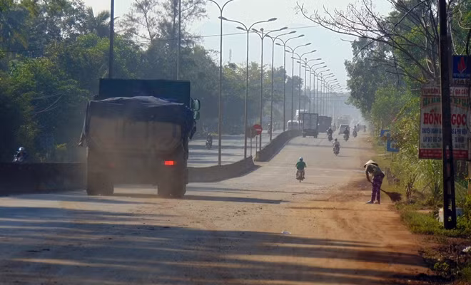 Đất, bụi bẩn vương vãi trên QL1A kéo dài hàng trăm mét do xe tải chở đất san lấp gây ra.