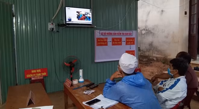 Tranh thủ lúc rãnh rỗi, cán bộ tại chốt kiểm soát theo dõi tình hình dịch COVID-19 qua sóng truyền hình.