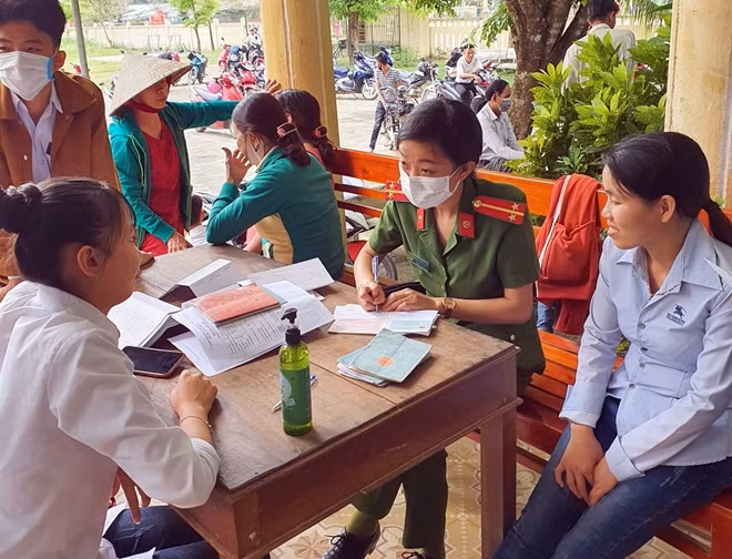 Nữ cán bộ Công an huyện Tiên Phước mang khẩu trang, trang bị bình sát khuẩn khi làm chứng minh nhân dân cho người dân.