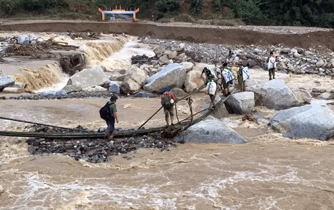 Đoàn công tác của Công an huyện Phước Sơn vượt dòng suối chảy xiết để vào xã Phước Lộc tiếp tế lương thực.