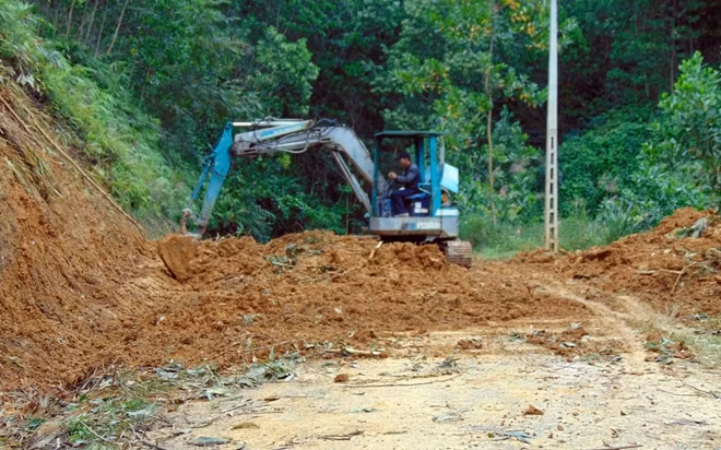 Xe múc dọn dẹp đất đá sạt lở trên tuyến đường nối từ xã A Tiêng đi xã A Nông.