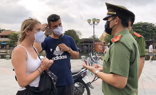 Đoàn viên thanh niên Công an tỉnh Quảng Nam tuyên truyền về quy định đeo khẩu trang ở nơi công cộng cho du khách tại TP Hội An.