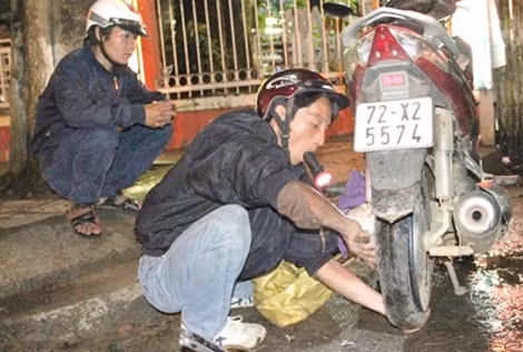 Anh Đặng Khánh Duy đang vá xăm xe cho người gặp hoạn nạn trong đêm.