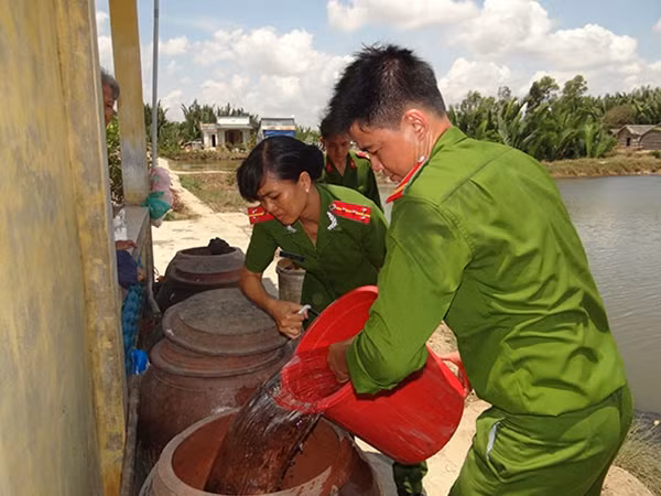 Lực lượng ĐVTN, Hội phụ nữ Công an huyện Cần Giuộc triển khai đường ống dẫn nước từ ghe lên hồ chứa nước các hộ dân.
