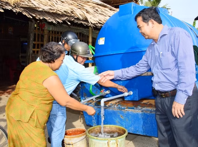 Ông Trần Quốc Thắng (phải), Chủ tịch UBND huyện Châu Thành xuống địa phương chỉ đạo cấp nước sạch miễn phí cho người dân sử dụng.