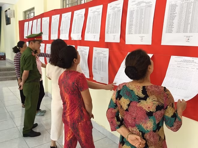 Các cử tri đang háo hức nghiên cứu danh sách đại biểu tại một điểm bầu cử số 7, phường Phúc Diễn, quận Bắc Từ Liêm.
