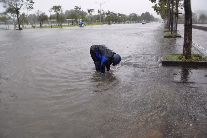 Người dân vớt rác khai thông cống thoát nước bên đường