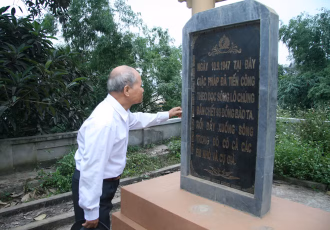 Ông Trần Văn Giá, một nhân chứng trong vụ thảm sát năm 1947, bên tấm bia tưởng niệm tại làng An Đạo