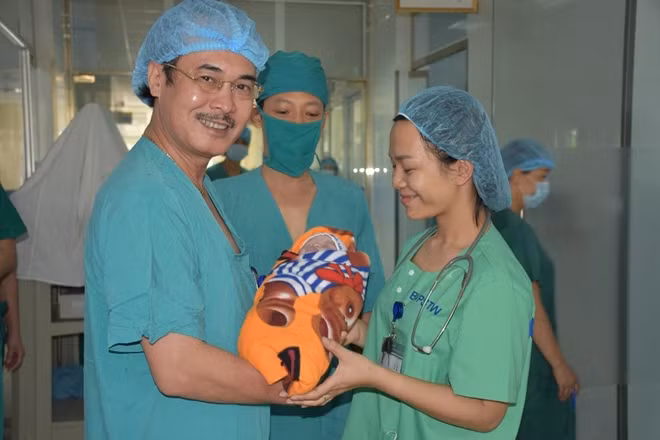 Ca mổ đẻ thành công, PGS. Vũ Xuân Phú trao cháu bé cho bác sĩ BV Phụ sản đưa về chăm sóc,