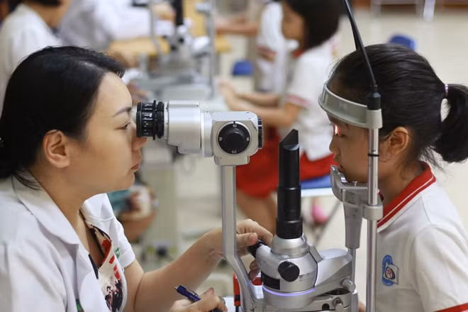 Bác sĩ kiểm tra mắt cho học sinh để phát hiện sớm tật khúc xạ học đường
