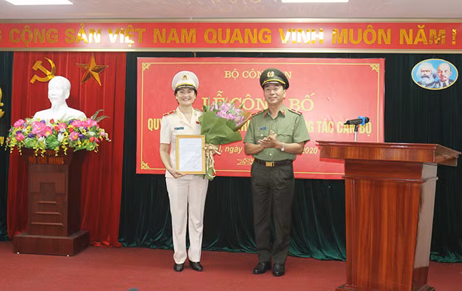 Thứ trưởng Trần Quốc Tỏ trao quyết định và tặng hoa chúc mừng Thiếu tướng Ngô Thị Hoàng Yến.