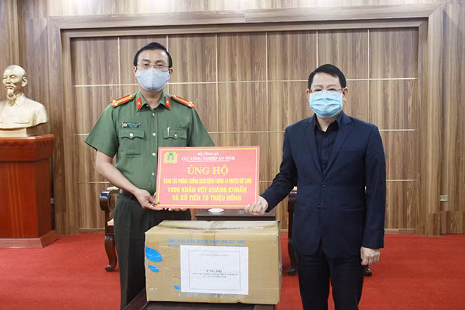 Đồng chí Hoàng Anh Tuấn, Phó Chủ tịch UBND huyện Mê Linh tiếp nhận khăn ướt kháng khuẩn và 70 triệu đồng từ Cục Công nghiệp An ninh.