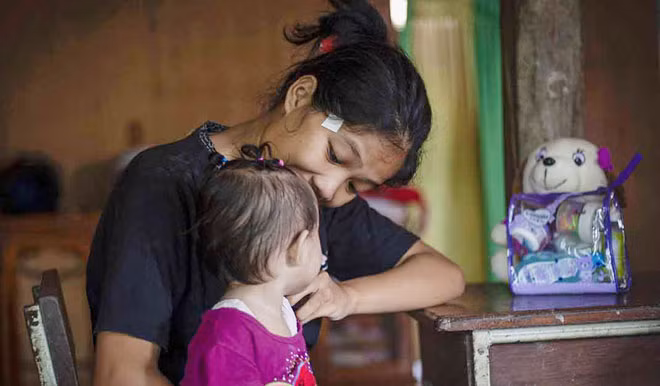 Người mẹ trẻ chưa đủ 18 tuổi Nurlina cùng cô con gái của mình ở Galung Lombok, tây Sulawesi, Indonesia. Người mẹ trẻ chưa đủ 18 tuổi Nurlina cùng cô con gái của mình ở Galung Lombok, tây Sulawesi, Indonesia.