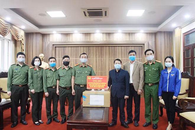 Trung tá Nguyễn Mạnh Cường, Phó Cục trưởng Cục Công nghiệp An ninh trao số khăn ướt kháng khuẩn và 70 triệu đồng cho đại diện BCĐ phòng chống dịch COVID-19 huyện Mê Linh
