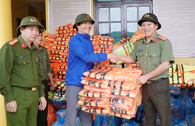 Lãnh đạo Công an tỉnh trao áo phao cho người dân vùng lũ.