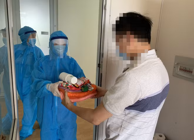Nhân viên y tế Bệnh viện Công an thành phố Hà Nội phát đồ dùng cá nhân cho một trường hợp F1 thuộc diện cách ly tập trung.