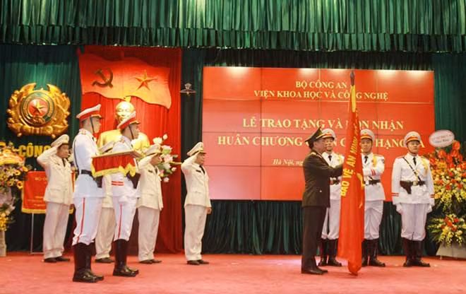 Thừa ủy quyền của Chủ tịch nước, Thứ trưởng Trần Quốc Tỏ gắn Huân chương Quân công hạng Ba lên Cờ truyền thống của Viện KH&CN.