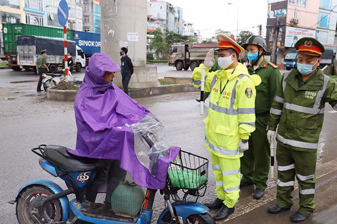 Tổ công tác yêu cầu một phụ nữ đi đường không đeo khẩu trang dừng xe để kiểm tra.