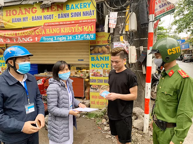 Tổ công tác phát khẩu trang cho một nam thanh niên ra đường không đeo khẩu trang và kết hợp lấy khai báo y tế.