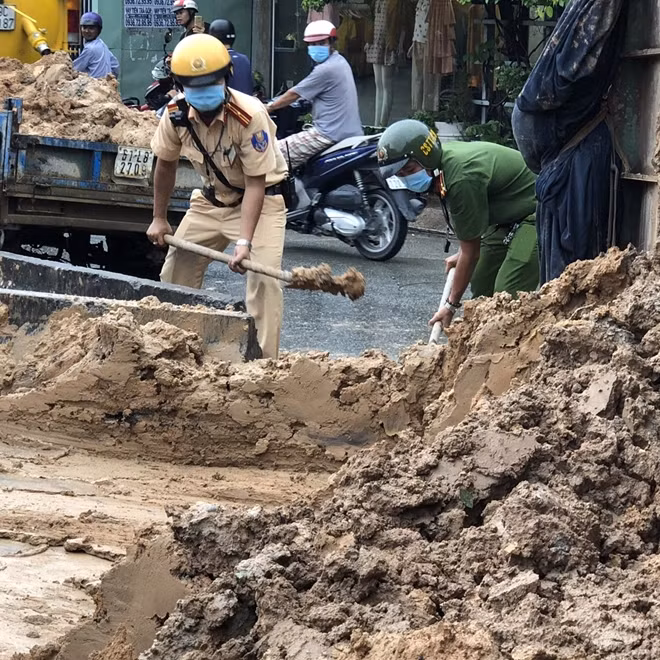 Cán bộ chiến sĩ CSGT-TT Công an quận 12 xúc đất, giải phóng mặt đường.