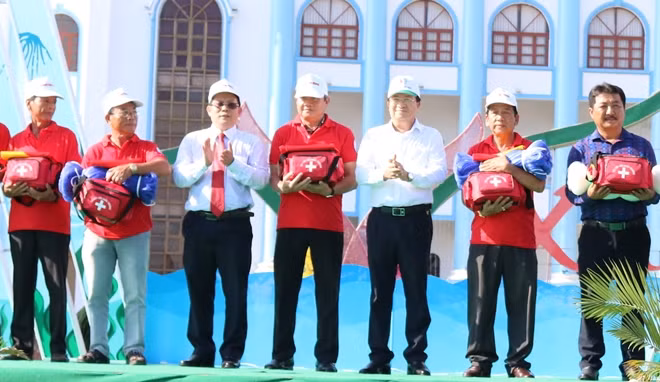 Phó Thủ tướng Trịnh Đình Dũng và ông Tô Đình Tuân, Tổng Biên tập Báo Người Lao Động trao cờ và lưới cho ngư dân trong chương trình "Một triệu lá cờ Tổ quốc cùng ngư dân bám biển".