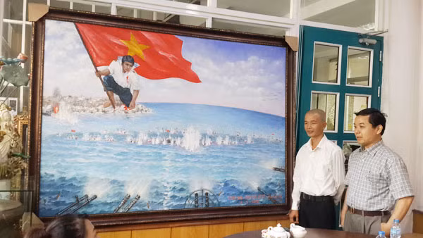 Họa sĩ Bùi Lệ Trang (trái) và ông Nguyễn Văn Phước - Giám đốc First News giới thiệu bức tranh “Gạc Ma - Vòng tròn bất tử”.