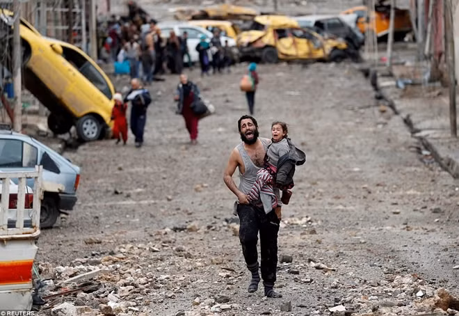 Một người đàn ông bế con gái chạy ra khỏi khu vực bị IS kiểm soát ở thành phố Mosul hồi tháng 3 năm nay. Cả hai đều gào thét vì hoảng sợ.