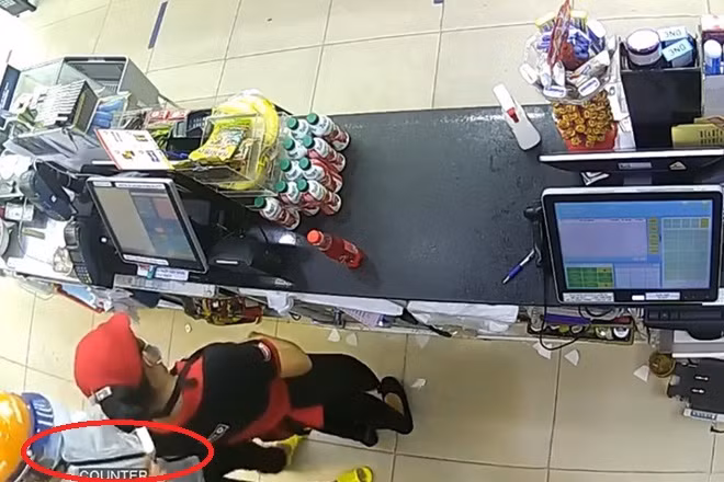 Hình ảnh tên cướp kề dao vào cổ nữ nhân viên do camera ghi lại.