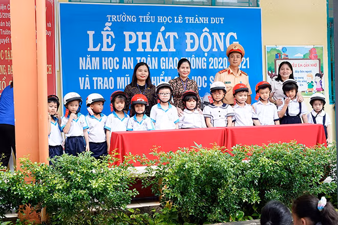 Đại úy Tuấn trong một buổi tuyên truyền pháp luật, tặng mũ bảo hiểm cho học sinh.