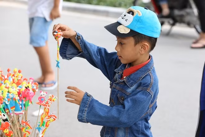 Nắm bắt thị trường, rất nhiều cửa hàng tại công viên Thủ Lệ đồng loạt bày bán các mặt hàng dành cho trẻ em vào dịp này. Trong ảnh một cậu bé đang chọn mua tò he.