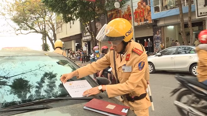 Tổ công tác CSGT Công an tỉnh Vĩnh Phúc dán thông báo xử phạt xe ôtô dừng đỗ không đúng nơi quy định.