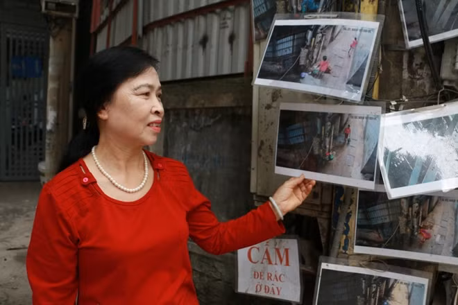 Tổ phó tổ dân phố 22 phường Dịch Vọng, quận Cầu Giấy Nguyễn Thị Dậu bên những bức ảnh góp phần giúp khu dân cư này thêm sạch đẹp.