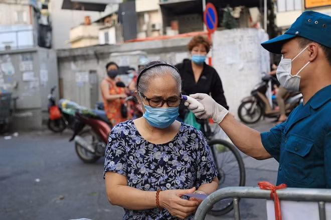 Lực lượng chức năng cũng tiến hành đo thân nhiệt đối với từng người dân vào chợ.