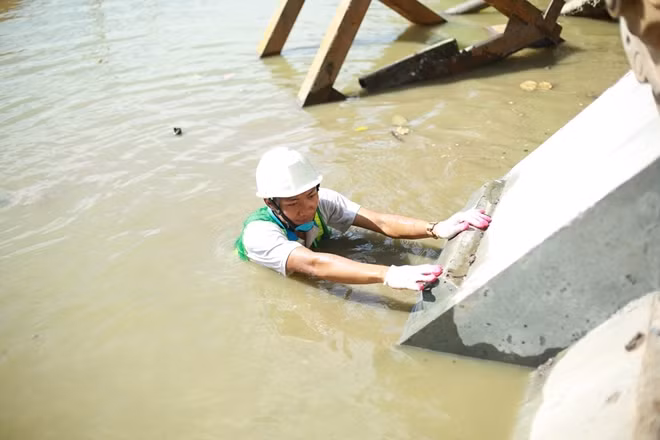 Ngoài ra còn có một người nữa phải lội xuống hồ để giúp đưa khối cấu kiện này vào vị trí một cách chính xác nhất.