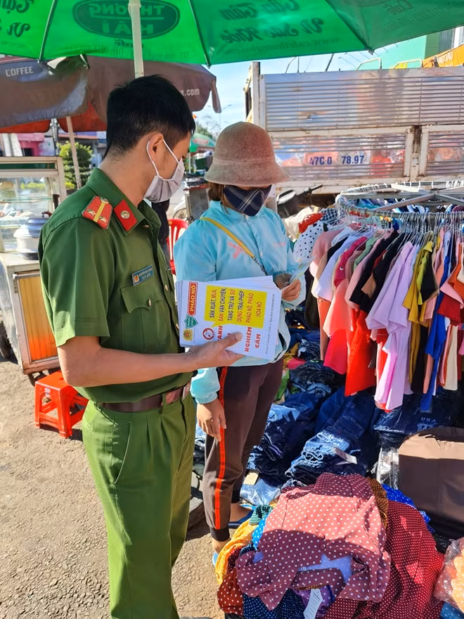 Cán bộ Công an huyện Đắk R’lấp phát tờ rơi tuyên truyền pháp luật tại Chợ Kiến Đức.