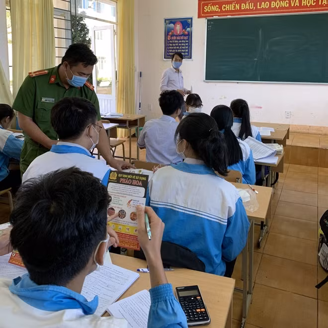 Cán bộ Công an huyện Đắk R’lấp phát tờ rơi tuyên truyền pháp luật tại Trường THPT Trường Chinh.