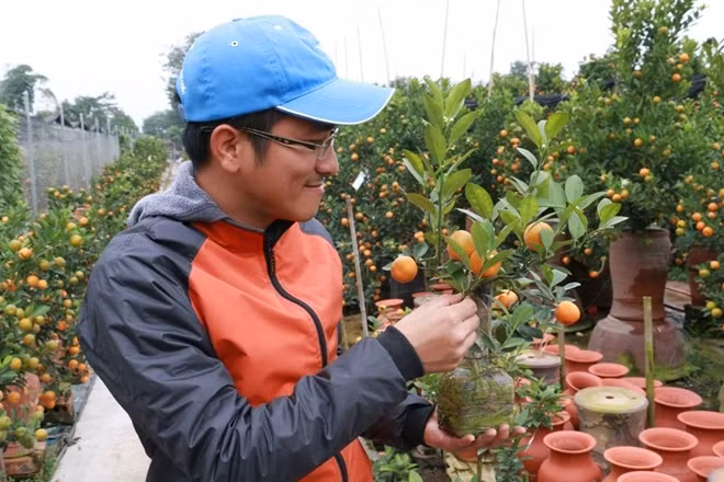 Anh Huy chủ vườn tác với một cây quất bon sai được trồng trong chai thủy tinh.