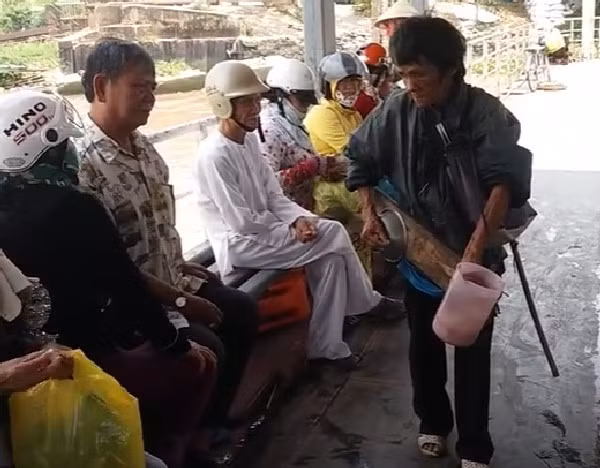 Ông Liêm ôm đàn đi hát rong trên khu vực chờ phà.