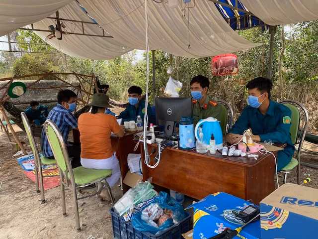 Cán bộ công an vận động người dân tự nguyện đưa con em mình (từ Campuchia về) vào trung tâm cách ly để được chăm sóc về y tế.